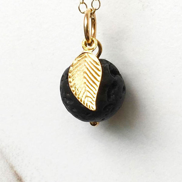 A close up of the lava bead and gold leaf charm on the diffuser necklace