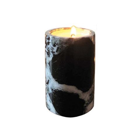A tea light candle holder made from black and white marble with a lit candle inside