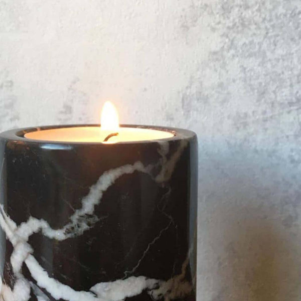 A lit tea light candle sat inside a black marble candle holder