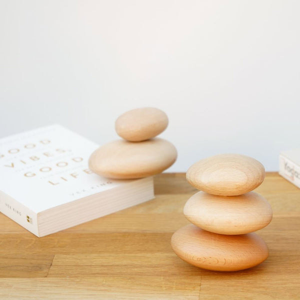5 wooden pebbles stacked on top of a table with a book