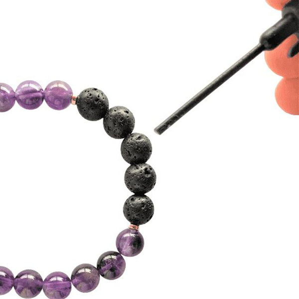Someone applying essential oil to the lava beads on the bracelet, with an applicator wand