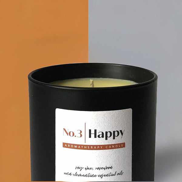 Black scented candle with orange and grey wallpaper
