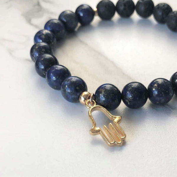 A blue lapis aromatherapy bracelet on a white marble background