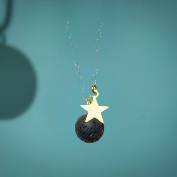 A moon and star diffuser necklace on a teal background