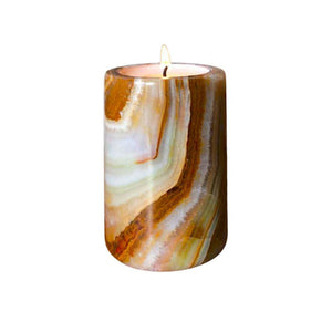 A striped, multi-coloured onyx stone candle, with a lit tea light candle inside