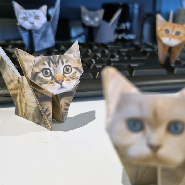 Origami paper cat figures on and around a computer keyboard