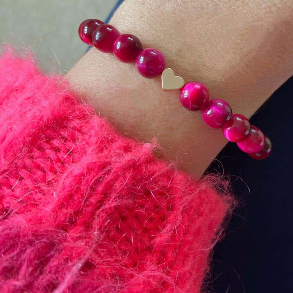 Woman wearing a pink jumper and pink tigers eye bracelet