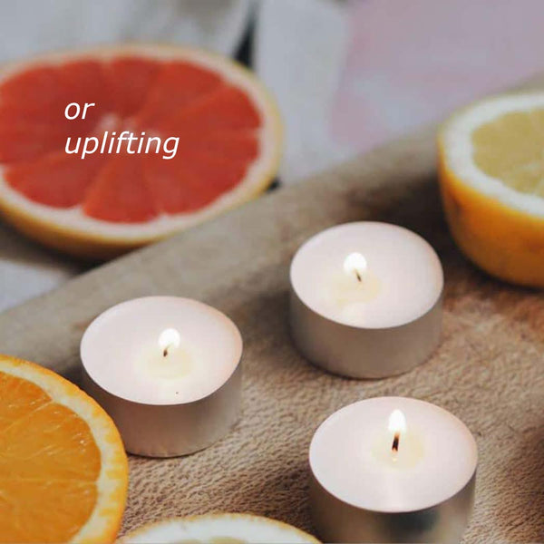 Three tea light candles next to a halved orange