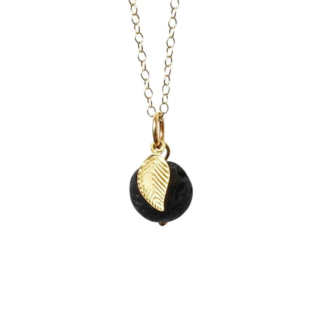 A round lava stone and golf leaf pendant attached to a gold chain
