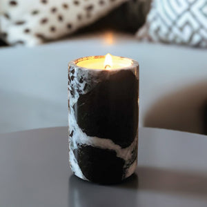 A black marble candle on a coffee table by a sofa
