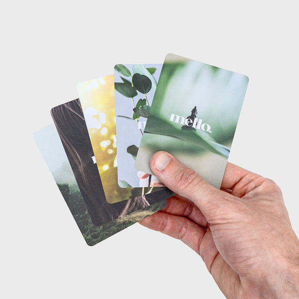Hand holding five cards with nature imagery and 'mello' branding.