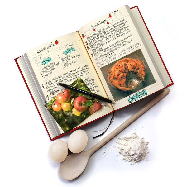 Open cookbook with recipe pages and ingredients on a white background
