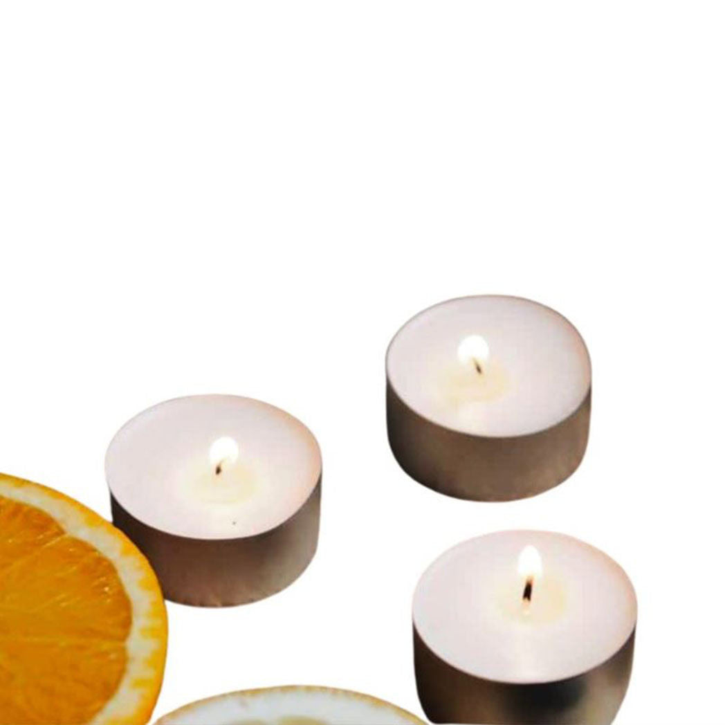 Three essential oil tea light candles lit next to a piece of orange