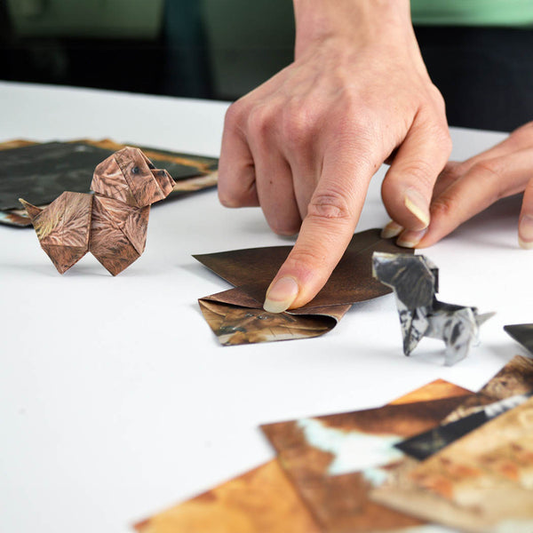 Person folding paper pups on a white table