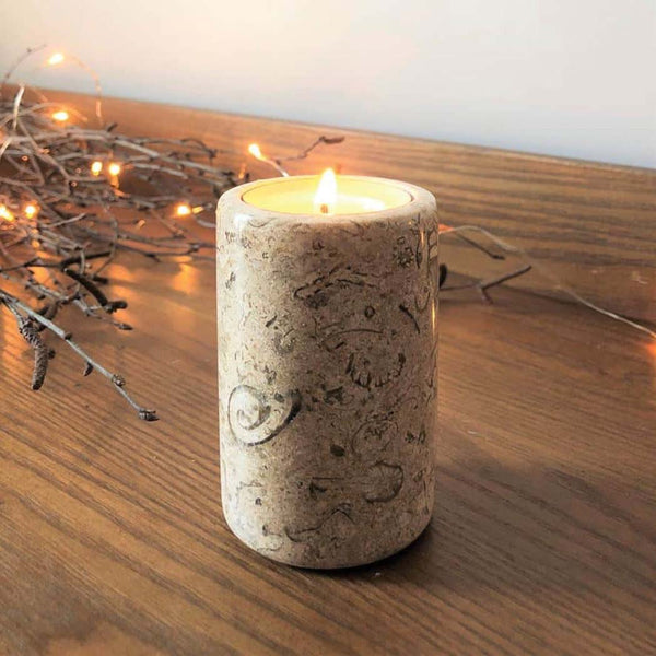 A fossil stone candle on a chest of drawers