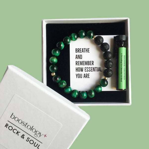 A green tigers eye and lava stone diffuser bracelet with the words "breathe and remember how essential you are"