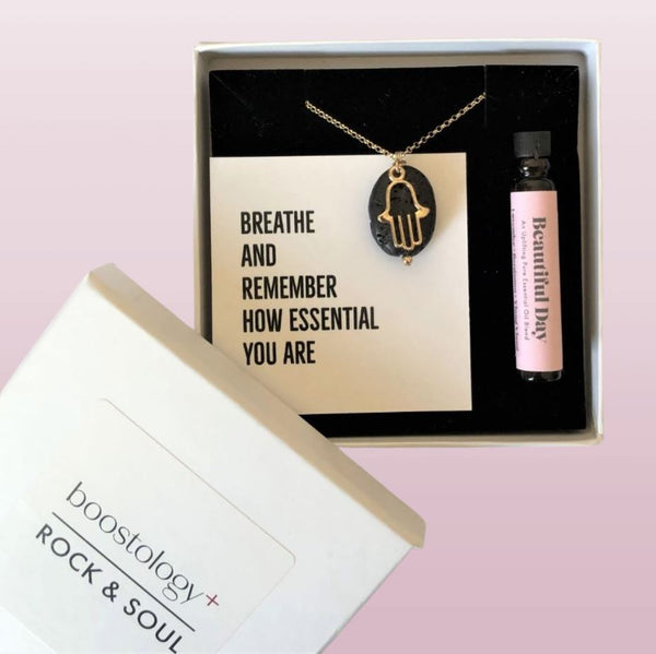 A hamsa diffuser necklace and essential oil in a white gift box