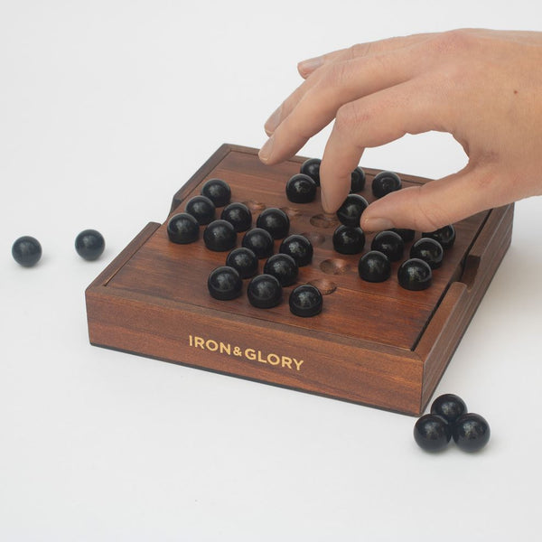Someone playing with a wooden Solitaire