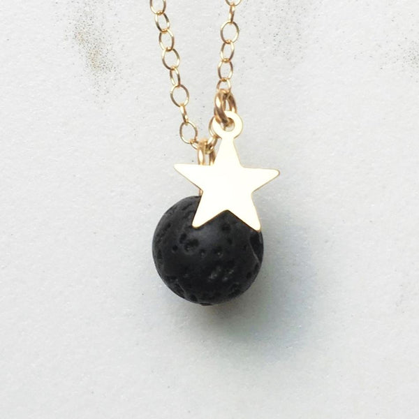 Gold star lava diffuser necklace on a white marble background