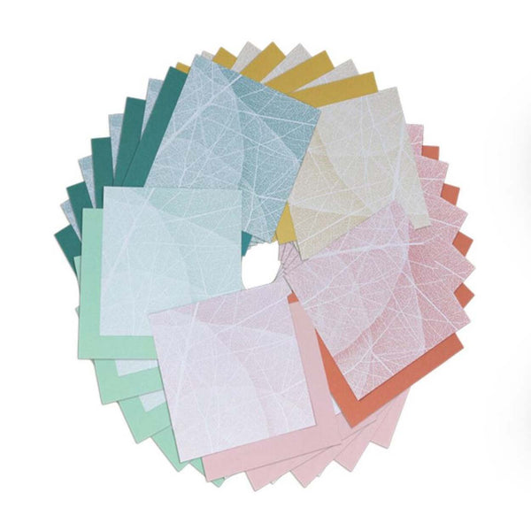 A wheel of different coloured origami paper showing the patterned underside of the paper