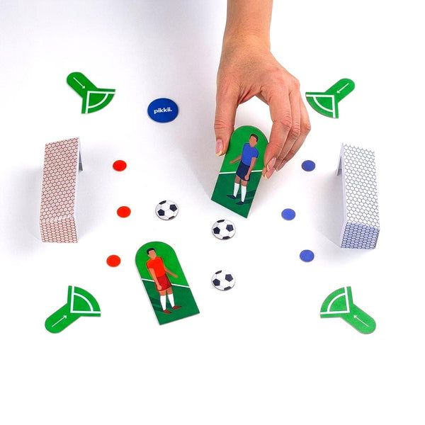Hand playing with the football themed game on a white surface