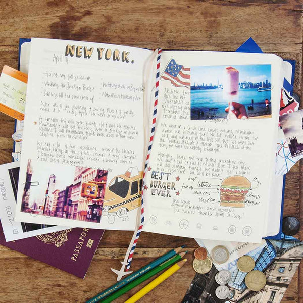 Travel journal with New York-themed pages and travel memorabilia on a wooden surface