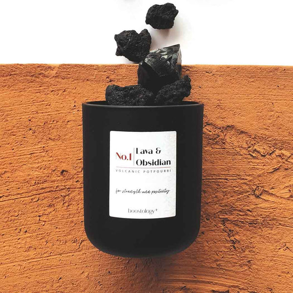 Black diffuser jar with obsidian rocks on a sandstone surface