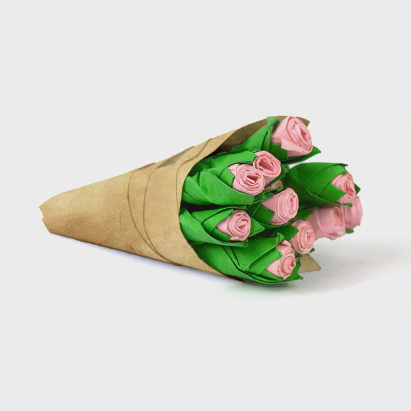 Bouquet of pink and green paper roses wrapped in brown paper on a white background