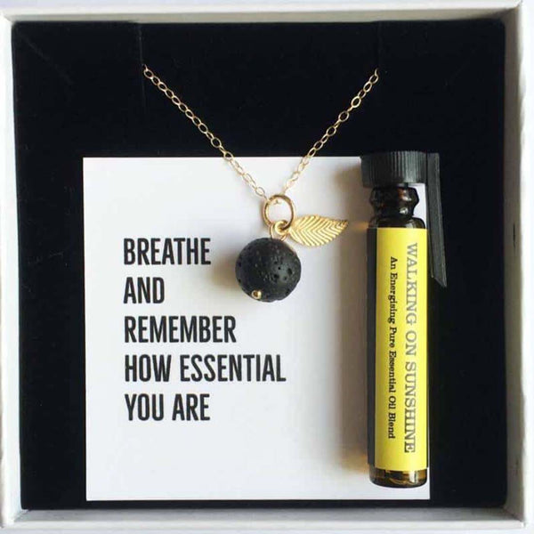 A gold leaf aromatherapy necklace with a bottle of essential oil, in a white gift box