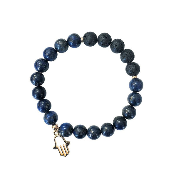 A diffuser bracelet made from blue lapis stones and black lava rock with a gold hamsa charm