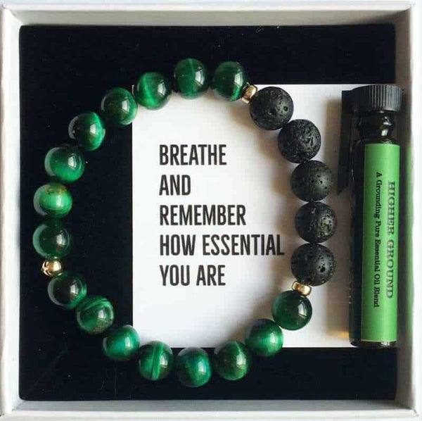 A green tigers eye and lava stone diffuser bracelet with a bottle of essential oil in a white gift box
