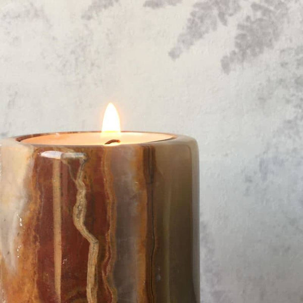 An Onyx stone tea light candle holder with a lit candle