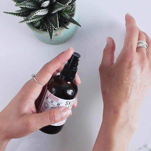 A woman spraying rose face mist onto her hand