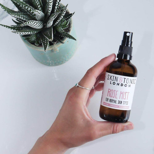 A woman holding a bottle of rose facial mist