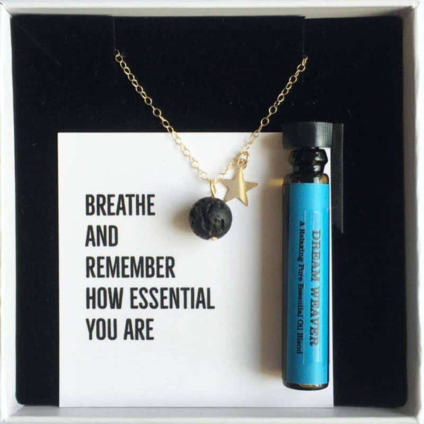 A gold star lava diffuser necklace with a bottle of essential oil in a white gift box