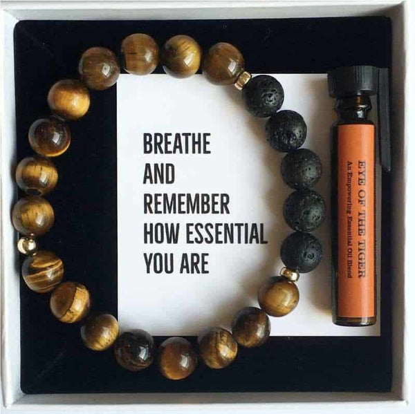 A tigers eye and lava stone diffuser bracelet with a bottle of essential oil in a white gift box